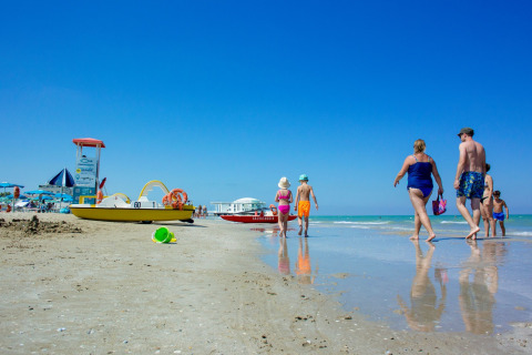 Gezinnen wandelen langs het strand bij Senigallia, met boten en blauwe lucht in de regio Marche, Italië.