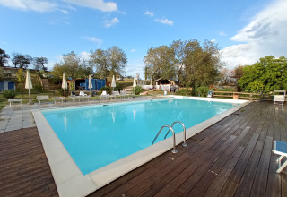 Außenpool mit Liegestühlen und Sonnenschirmen im Ferienpark Tenuta Tredici Ulivi in Marche, Italien.