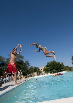 Enfants sautant dans une piscine sous le soleil au parc de vacances Tenuta Tredici Ulivi à Marche, Italie.