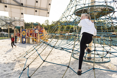 Bambini che giocano su un parco giochi sabbioso con rete da arrampicata a Recreatieoord Wilhelm Tell, Limburgo, Belgio.