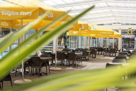 Buitenterras met gele parasols bij Recreatieoord Wilhelm Tell, Belgisch Limburg, met lege tafels.