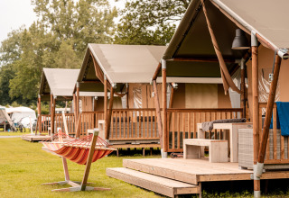 Rij van luxetenten met houten terras en hangmat op Recreatieoord Wilhelm Tell in Belgisch Limburg.