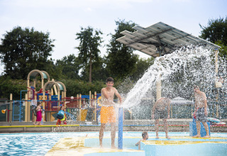 Junge spielt mit einer großen Wasserfontäne in einem Freibad im Recreatieoord Wilhelm Tell, Limburg, Belgien.