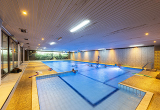 Indendørs swimmingpool i feriestedet Recreatieoord Wilhelm Tell i Limburg, Belgien, med familier der svømmer.