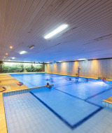 Piscina cubierta en Recreatieoord Wilhelm Tell, parque vacacional en Limburgo, Bélgica, con visitantes nadando.