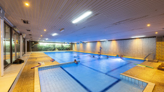 Overdekt zwembad op Recreatieoord Wilhelm Tell in Limburg, België, met zwemmende bezoekers bij het vakantiepark.