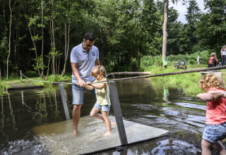 En mand og to børn leger på en vandplatform i en skov ved Recreatiepark de Lucht i Utrecht, Holland.