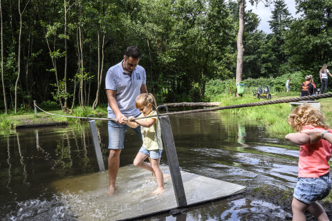 Ein Mann hilft zwei Kindern beim Überqueren einer Wasserplattform im Recreatiepark de Lucht, Utrecht, Niederlande.