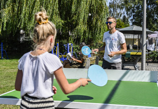 To personer spiller bordtennis udendørs i solskin på Recreatiepark de Lucht, Utrecht, Holland.