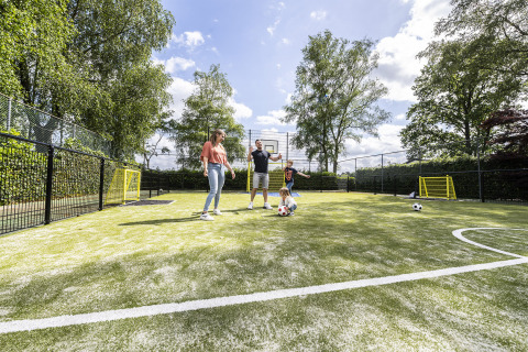Familie spielt auf einem Multifunktionssportplatz im Recreatiepark de Lucht, Utrecht, Niederlande.