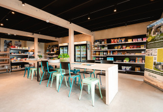 Bright shop interior at Vakantiepark De Nollen, North Holland, Netherlands, with tables, chairs and shelves.