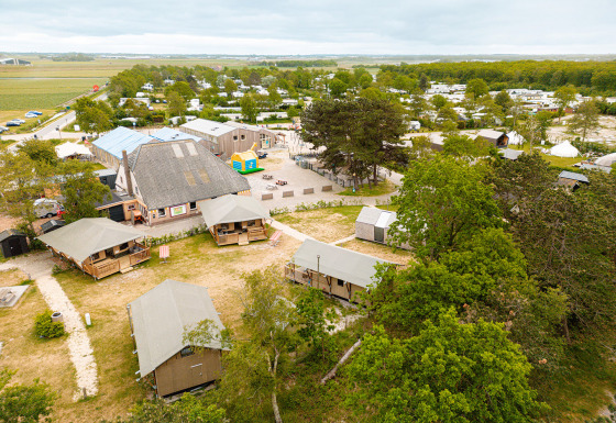 Aerial view of Vakantiepark De Nollen holiday park with tents, cabins, trees, and greenery in North Holland.