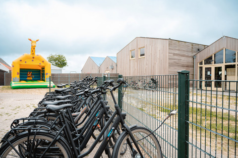 Cykler ved et hegn og en oppustelig giraf-hoppeborg på Vakantiepark De Nollen, Nordholland, Nederlandene.