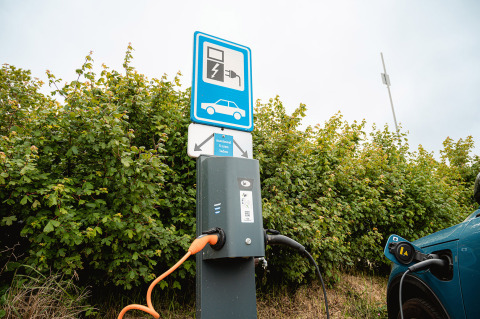 Ladestation til elbil på Vakantiepark De Nollen i Nordholland, med et skilt og bil til opladning.