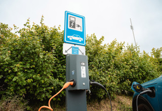 Laadpaal voor elektrische auto op Vakantiepark De Nollen, Noord-Holland, met een auto aan het opladen.