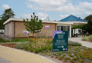 Ingang van Vakantiepark De Nollen in Noord-Holland, Nederland, met verwelkomingsbord en modern gebouw.