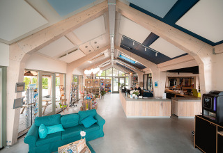 Moderne receptie met houten balken en zetel in Vakantiepark De Nollen, vakantiepark in Noord-Holland, Nederland.