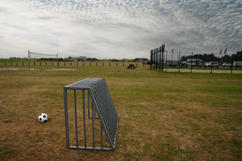 Ein Fußball liegt auf einer Wiese neben einem Metallständer im Vakantiepark De Nollen, Nordholland, Niederlande.