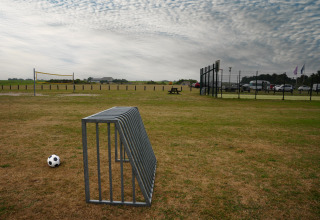 Ein Fußball liegt auf einer Wiese neben einem Metallständer im Vakantiepark De Nollen, Nordholland, Niederlande.