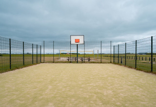 Außen-Basketballfeld mit Zaun, Volleyballfeld und Picknicktisch im Ferienpark De Nollen, Niederlande.