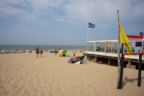 Escena de playa en Vakantiepark De Nollen en Holanda del Norte, Países Bajos, con visitantes y pabellón.