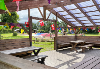 Udendørs siddeområde på Ballum Camping, Danmark, dekoreret med flag og farverige vimpler om sommeren.