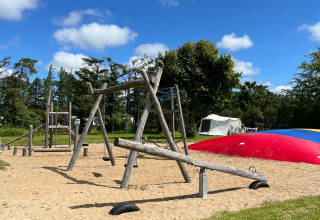 Aire de jeux avec balançoires et bascules au Ballum Camping, Danemark, sous un ciel bleu et ensoleillé.