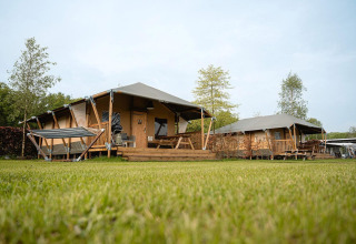 Tienda safari Villatent Cottage en Holiday Park Ackersate, Países Bajos, con césped y terraza de madera.