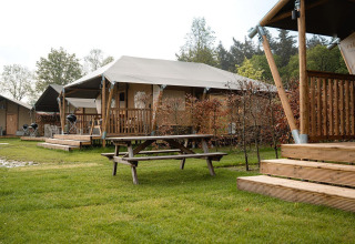 Safari-Zelte namens Villatent Cottage im Holiday Park Ackersate, Niederlande, mit Holzterrassen und Rasenfläche.