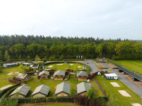 Vista aérea de las tiendas safari Villatent Nomad en Holiday Park Ackersate, junto a un bosque en los Países Bajos.