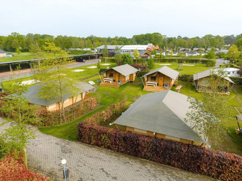 Vista aérea de tiendas safari Villatent Nomad en Holiday Park Ackersate, Países Bajos, rodeadas de zonas verdes.