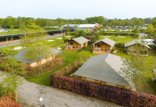 Vista aérea de tiendas safari Villatent Nomad en Holiday Park Ackersate, Países Bajos, rodeadas de zonas verdes.