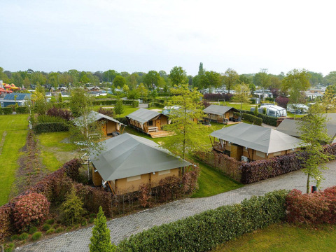 Vista aérea de las tiendas safari Villatent Nomad en Holiday Park Ackersate, Países Bajos, rodeadas de vegetación.
