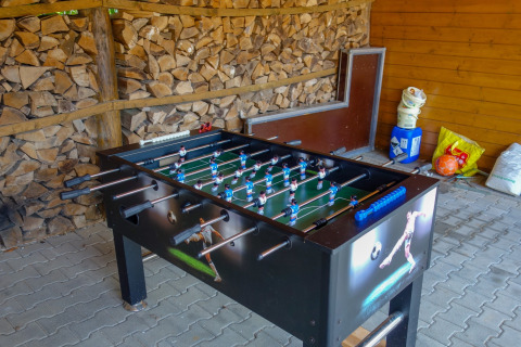 Tafelvoetbaltafel in een schuurtje met gestapeld brandhout op Camping Bockenauer Schweiz in Duitsland.