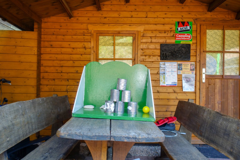 Dosenwurfspiel auf einem Picknicktisch vor einer Holzhütte auf dem Campingplatz Bockenauer Schweiz.