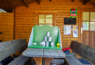 Juego de lanzar latas sobre una mesa de picnic frente a una cabaña en Camping Bockenauer Schweiz, Alemania.