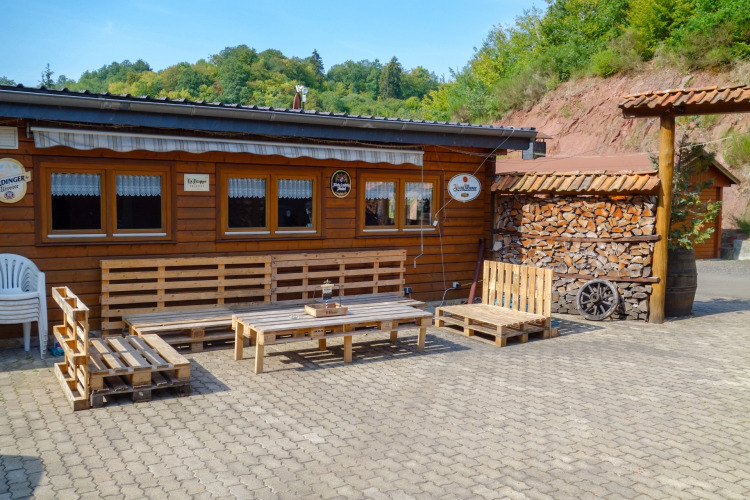 Outdoor seating area at Camping Bockenauer Schweiz with pallet furniture and firewood in Rhineland-Palatinate, Germany.