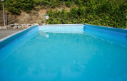 Et rektangulært swimmingpool ved Camping Bockenauer Schweiz i Rheinland-Pfalz omgivet af natur og grønt.