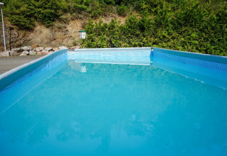 Piscina rettangolare al Camping Bockenauer Schweiz in Renania-Palatinato, circondata da verde.