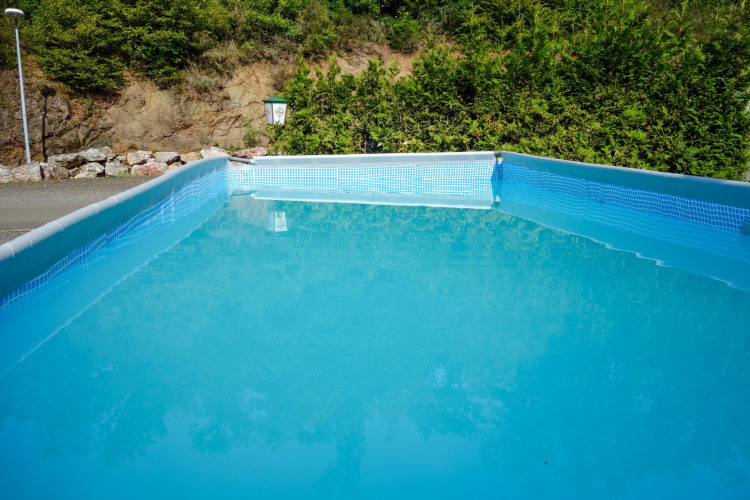 A rectangular swimming pool at Camping Bockenauer Schweiz in Rhineland-Palatinate, surrounded by greenery.