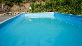 Piscina rectangular en Camping Bockenauer Schweiz, Renania-Palatinado, rodeada de vegetación y naturaleza.