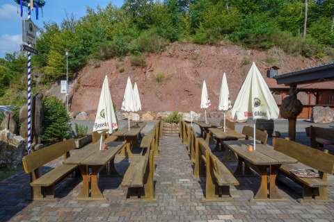 Outdoor beer garden with wooden benches, tables, and umbrellas at Camping Bockenauer Schweiz, Germany.