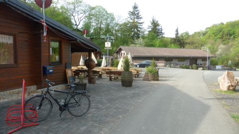 Außenszene im Camping Bockenauer Schweiz mit Fahrradständer, Holzhütten und Natur in Rheinland-Pfalz.