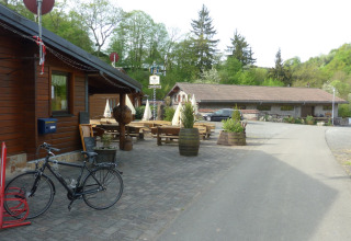 Vista esterna al Camping Bockenauer Schweiz con bici, tavoli di legno e vegetazione in Germania.