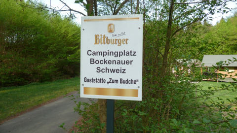 Skilt ved Camping Bockenauer Schweiz, et ferieområde i Rhinland-Pfalz, Tyskland, omgivet af natur.