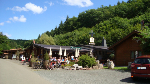 Fahrräder und Gäste vor einer Hütte im Grünen am Camping Bockenauer Schweiz, Rheinland-Pfalz.