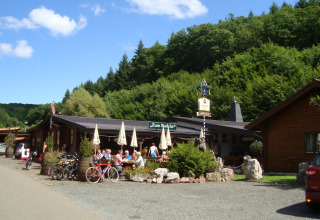 Ciclisti e ospiti seduti all'aperto vicino a bungalow nel Camping Bockenauer Schweiz, Germania.
