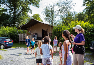 Kinderen spelen buiten tenten op Camping de Chênefleur, vakantiepark in Belgisch Luxemburg, België.