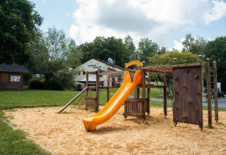 Speeltuin met gele glijbaan en klimwand bij Camping de Chênefleur vakantiepark in Luxemburg, België.