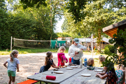 Bambini fanno lavoretti all'aperto a un tavolo nel Camping de Chênefleur, parco vacanze in Lussemburgo belga.